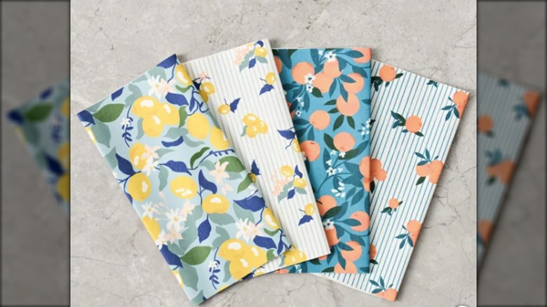 Four of Costco's Not-A-Paper Towels in "Orchard Grove" print are fanned out on a kitchen counter.