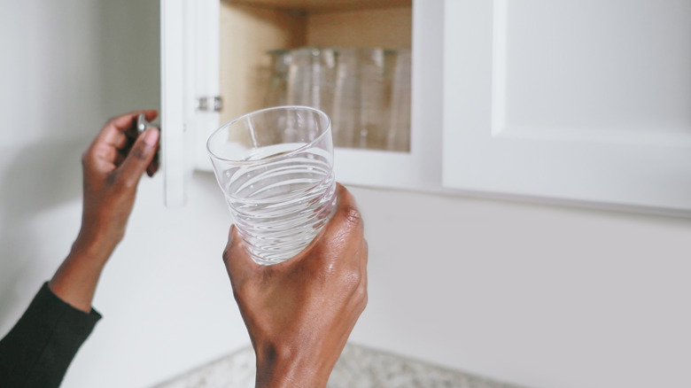A person pulling a glass out of a cabinet