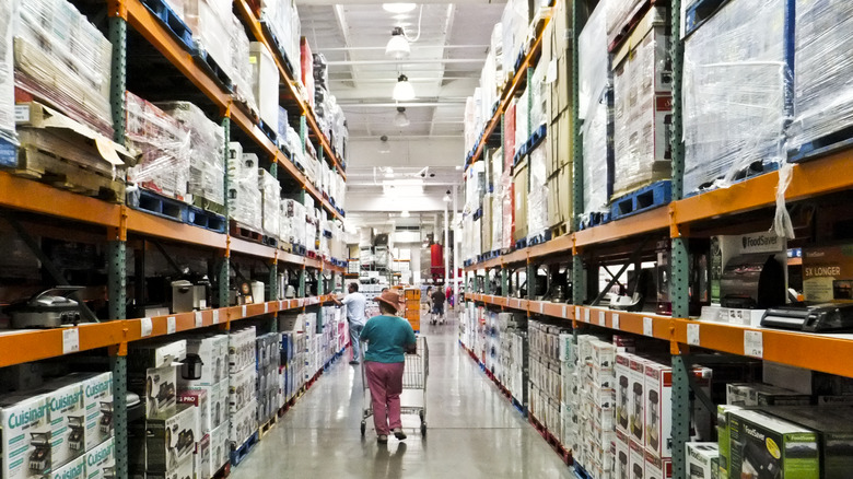 Shopper pushing cart in Costco aisle.