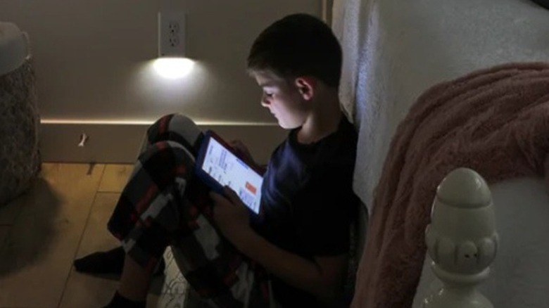 Boy reading a tablet near an LED outlet cover