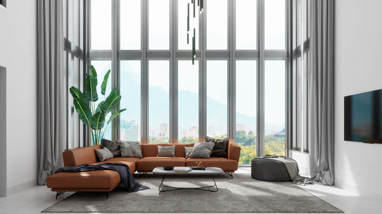 sofa in front of very large floor to ceiling windows in a modern apartment
