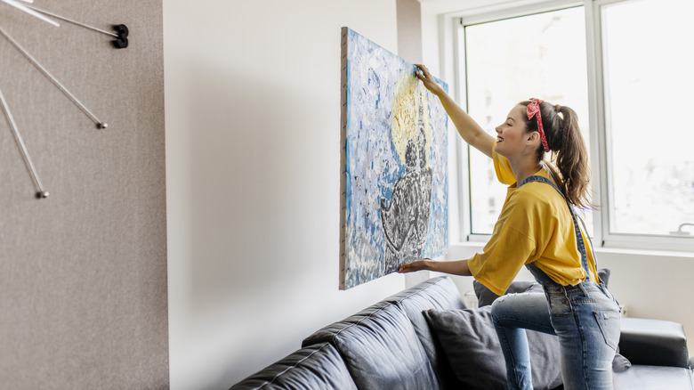 Young woman hanging picture on a wall