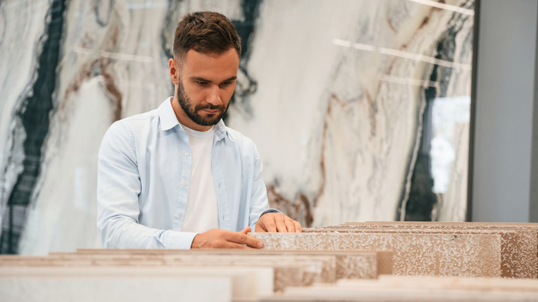 A man looks through slabs of marble at a showroom