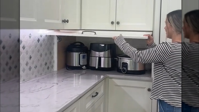 woman opening a small appliance garage door on her countertop