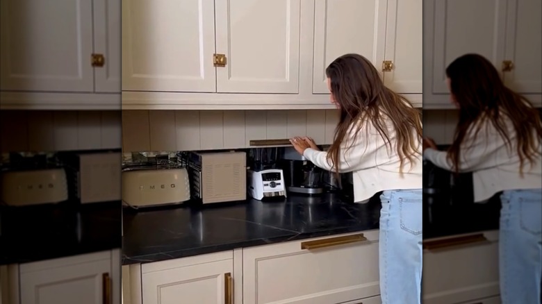woman opening long appliance garage door in kitchen