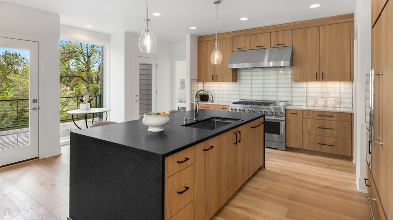 modern kitchen wood cabinets with black stone island countertop and white perimeter countertops