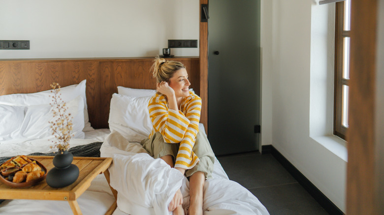 Woman smiling in bed looking out of window
