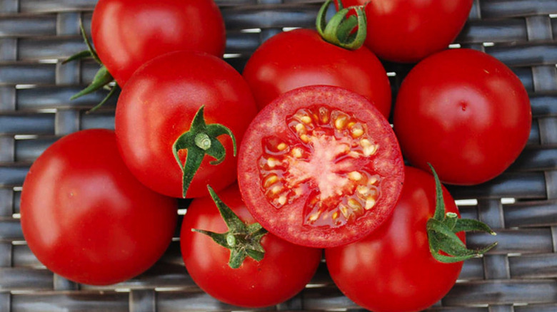 Small pile of BadaBing! F1 tomatoes in a woven basket with one cut in half and the ripe center showing