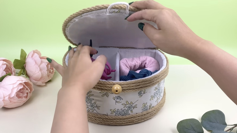 A person put scrunchies and other hair accessories into a fabric-lined DIY box.
