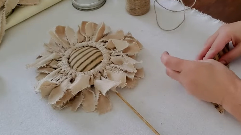 A rustic sunflower made out of scrap fabric and a canning lid