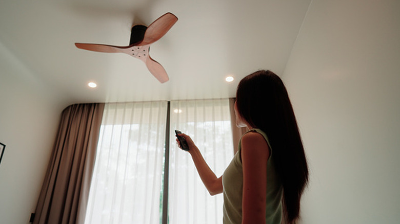 A woman turning on her ceiling fan