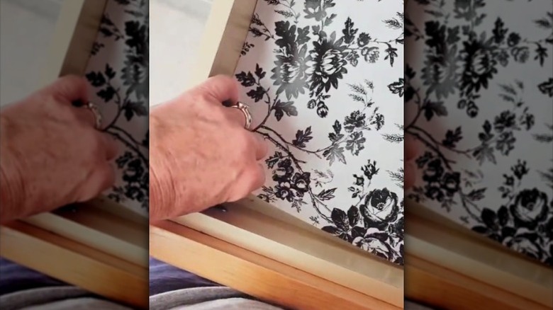 Woman putting black and white floral drawer liner in kitchen drawer