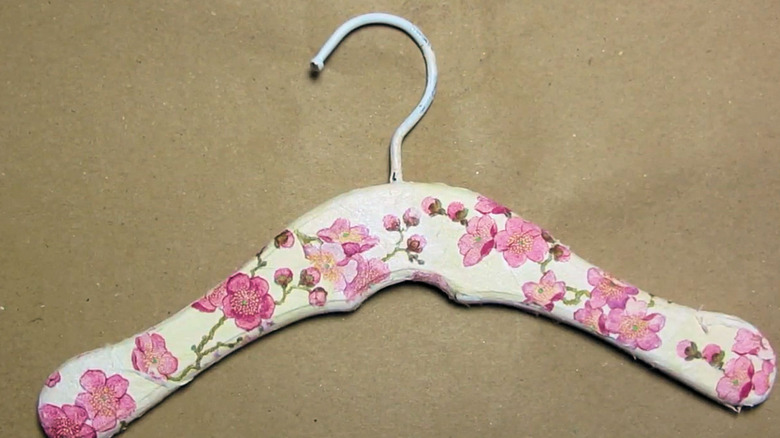A wooden hanger decorated with floral design.