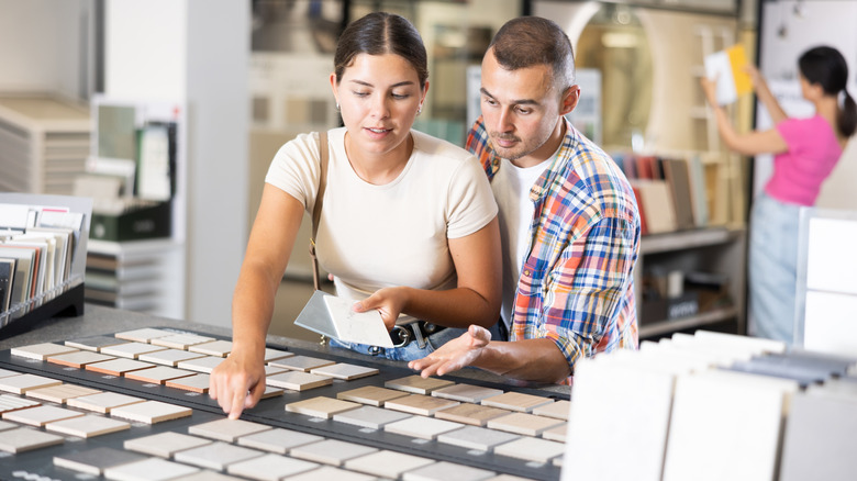 Couple picking out kitchen tiles from an assortment of samples.