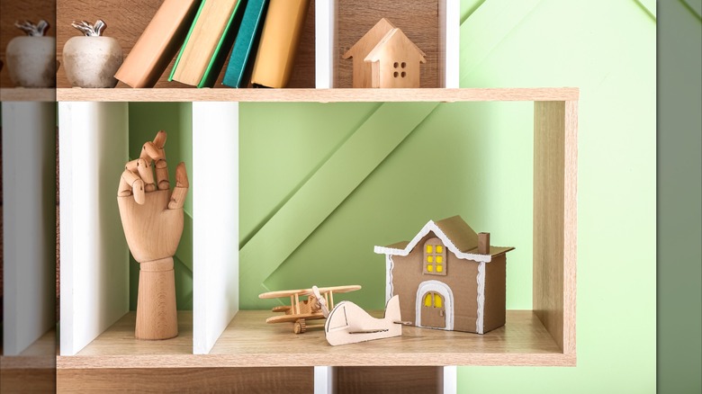 shelf unit with books, wooden hand, cardboard house and planes, etc.