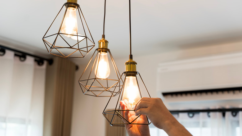 Person replacing light bulb on a pendant lamp