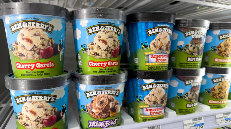A collection of Ben & Jerry's ice cream containers stacked on supermarket shelves.
