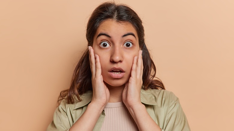 Scared woman with hands on her face