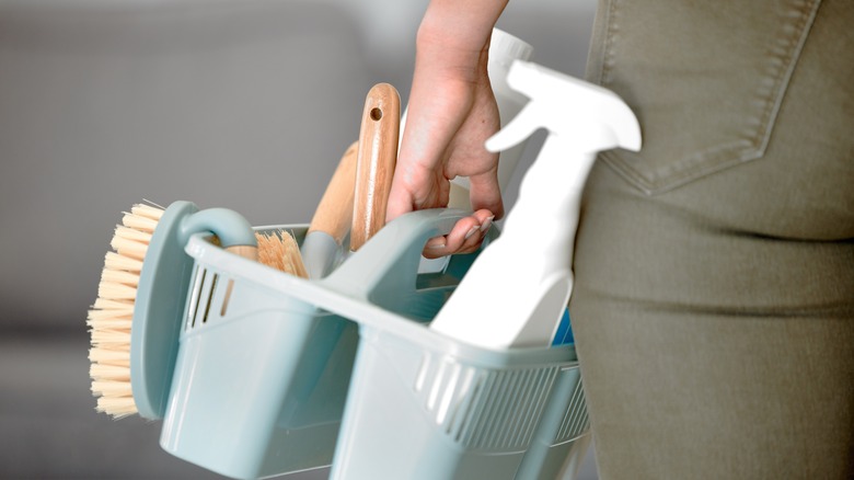 Holding tote of cleaning supplies