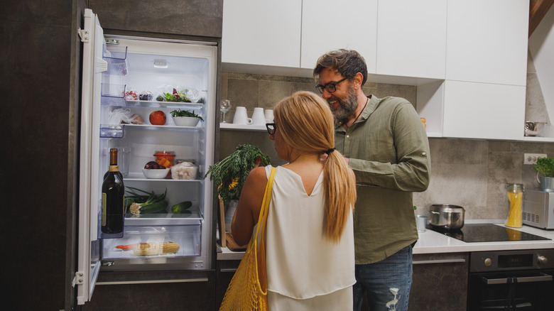 Couple organizing groceries in fridge