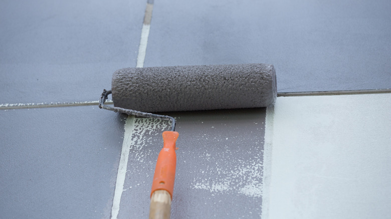 Rolling gray paint on white tile floor