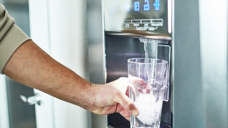 Man getting water from fridge dispenser