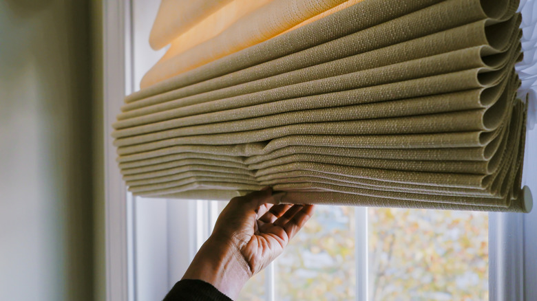 hand holding roman shades