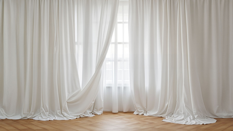 White pleated curtains extended towards middle of window, layered over a sheer curtain
