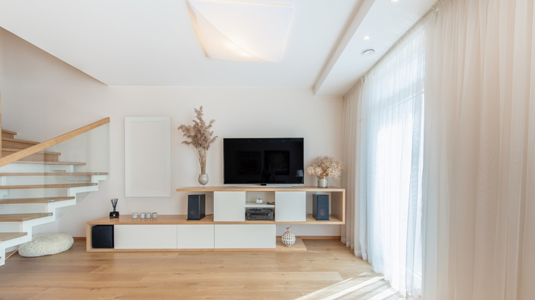 neutral colored living room with floor to ceiling curtains in neutral color over window