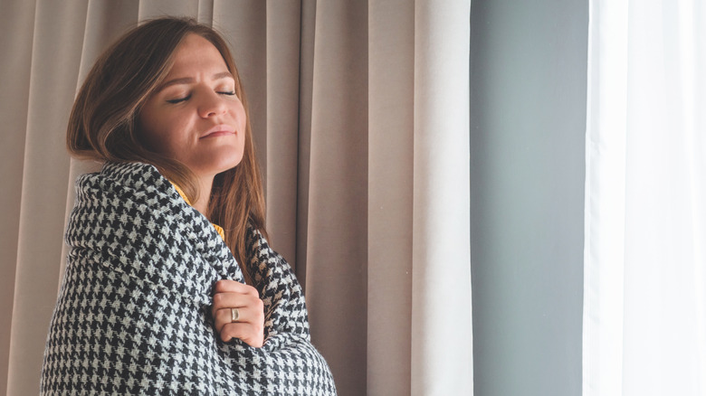 woman in blanket in front of curtains