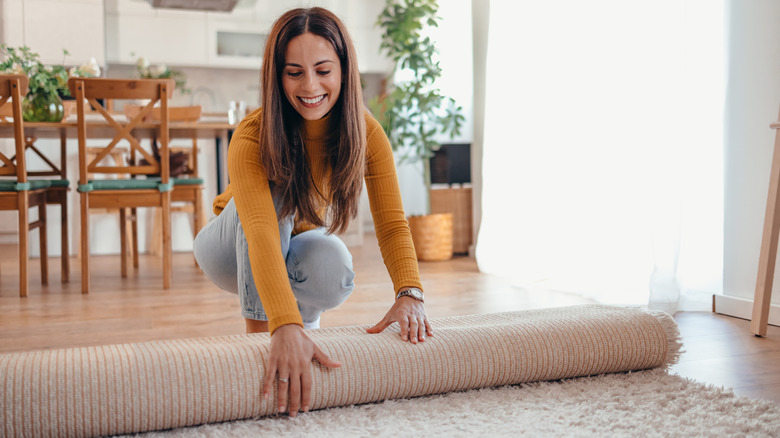 Woman unrolling new area rug in living room