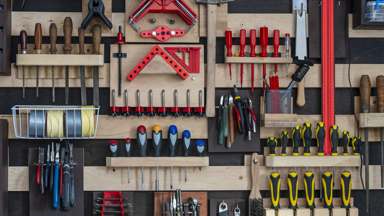 A wall with French cleats full of various tools and tool holders