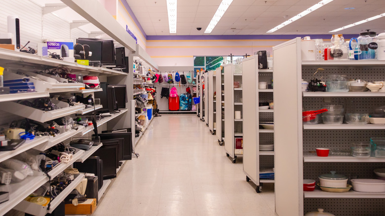 The outside aisle of a thrift store with lots of kitchen and household items on the shelves.