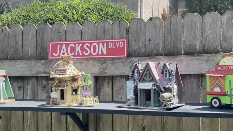 Bird feeders sitting on a shelf along a fence with the sign "Jackson Blvd" behind