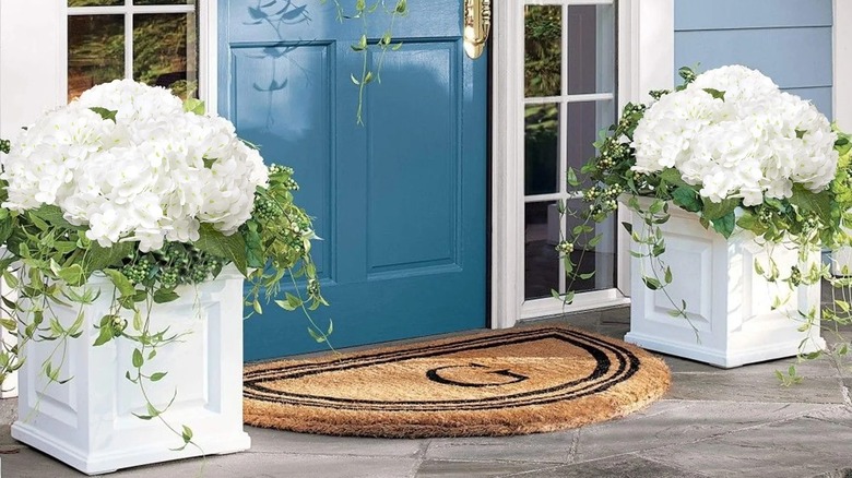 Faux white hydrangeas in a white planter on a front porch