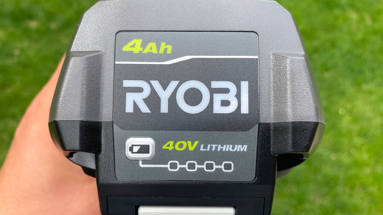 Hand holding Ryobi 40V lithium-ion battery pack outside