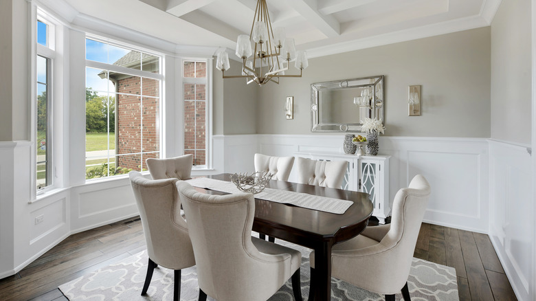 An all white formal dining room with large window.