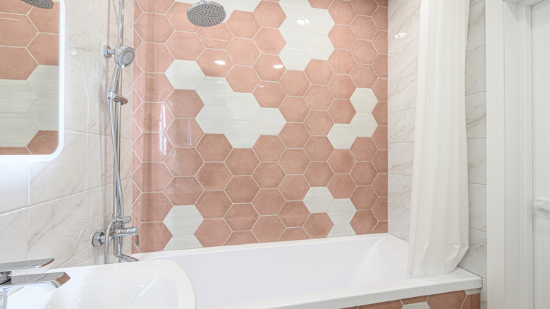 Pink hexagon shower tiles behind a bath.