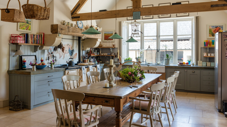 A rustic farmhouse style kitchen with a large dining table and uncovered windows.
