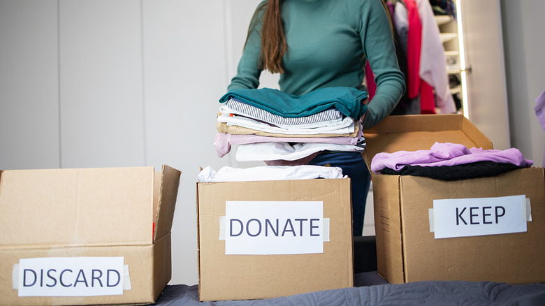 Woman sorting items into discard, donate, and keep boxes