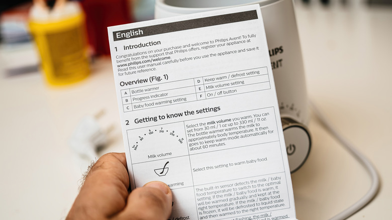 A man holding a user manual for an appliance.