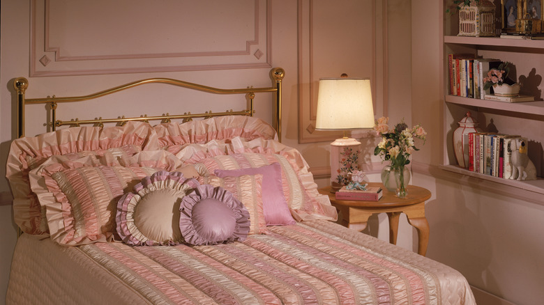 A 1980s bedroom with a pink color scheme and ruffled bedding