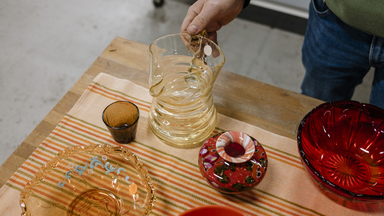 man looking at glass items on a thrift store table