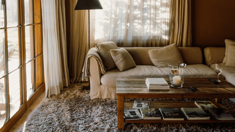 Living room with neutral tone, natural elements and wood coffee table and deep brown paint on the walls.