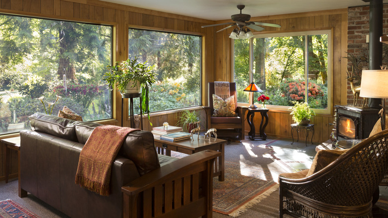 Living room interior of cabin style aesthetic, large windows reveal trees in the woods