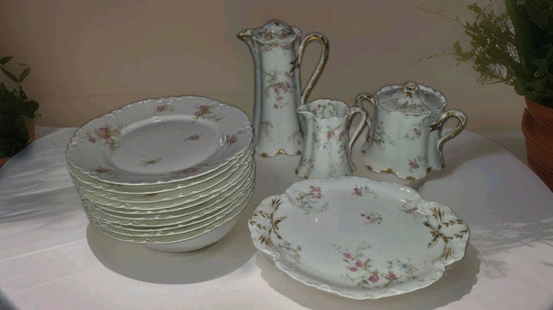 A white floral Limoges dish set featuring pitchers and plates on a table.