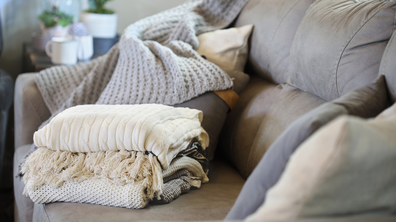 a pile of soft blankets on a messy sofa