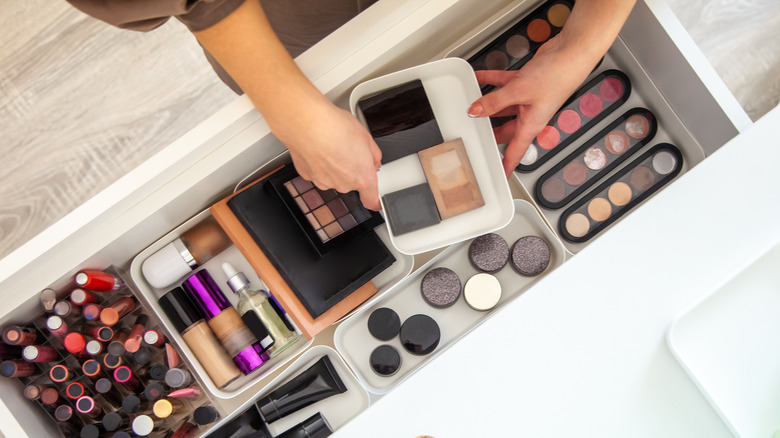 Woman taking out makeup from her vanity drawer