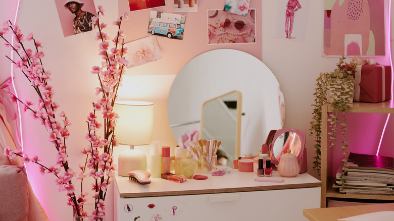A white and pink themed vanity corner with products on the table