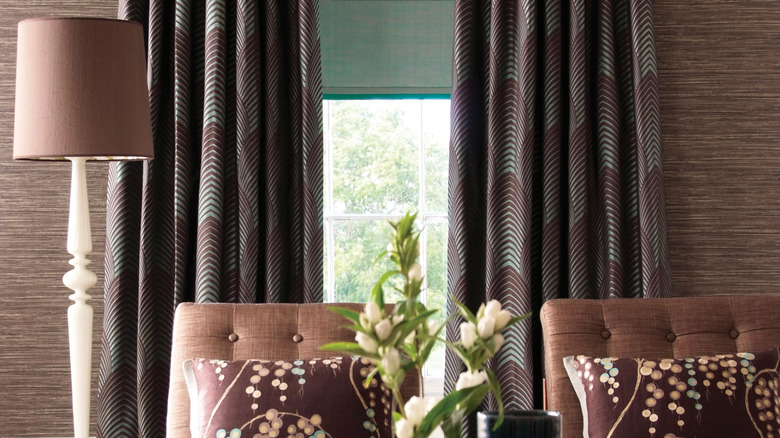 Window with brown patterned curtains and green blinds behind sofa
